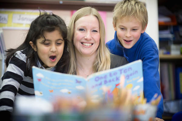 Picture of teacher and two primary-aged pupils looking at a book