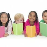 Four primary age children holding books and staring to camera